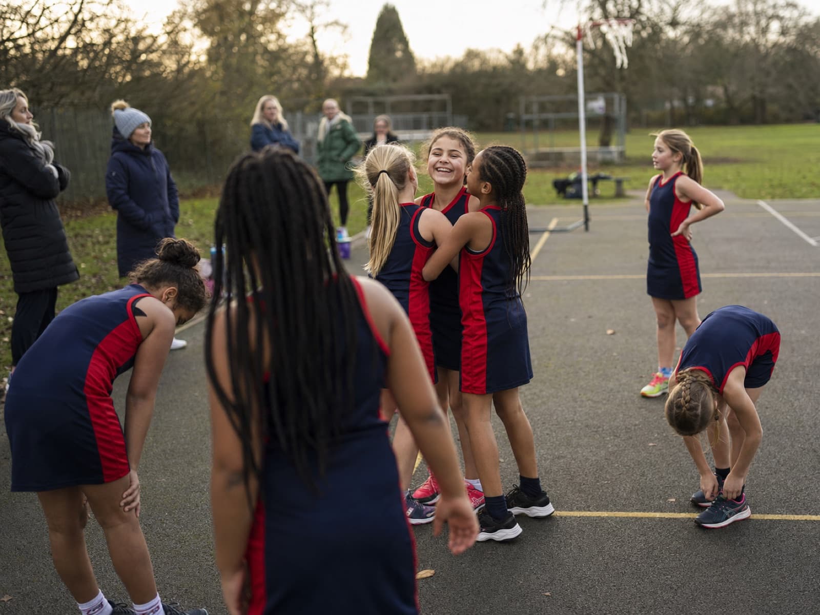 A grassroots girls' netball team celebrating together on a community court